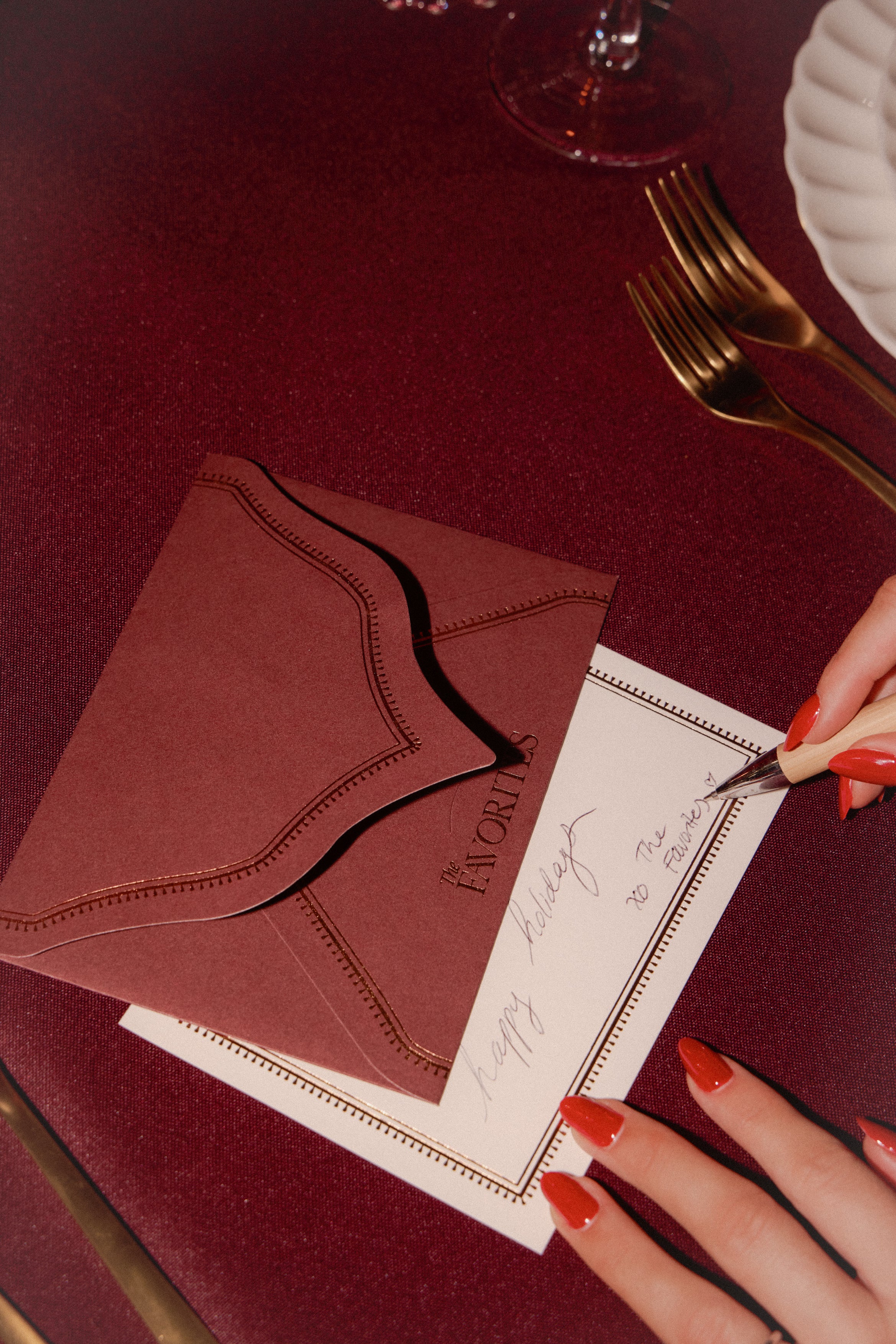 Red envelope and card on a red tablecloth with a hand holding a fork.